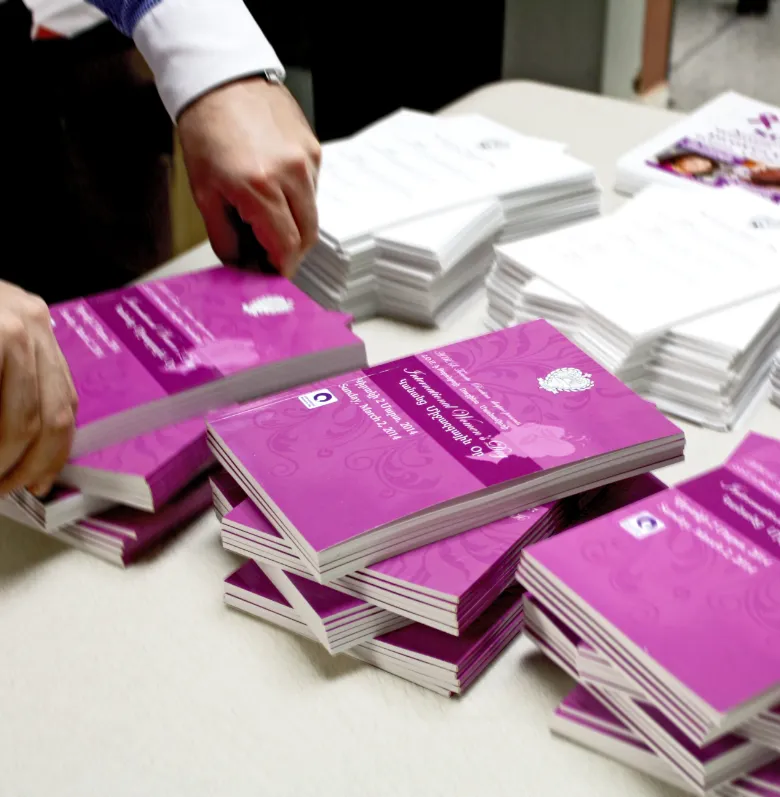 Freshly printed booklets being stacked by hand
